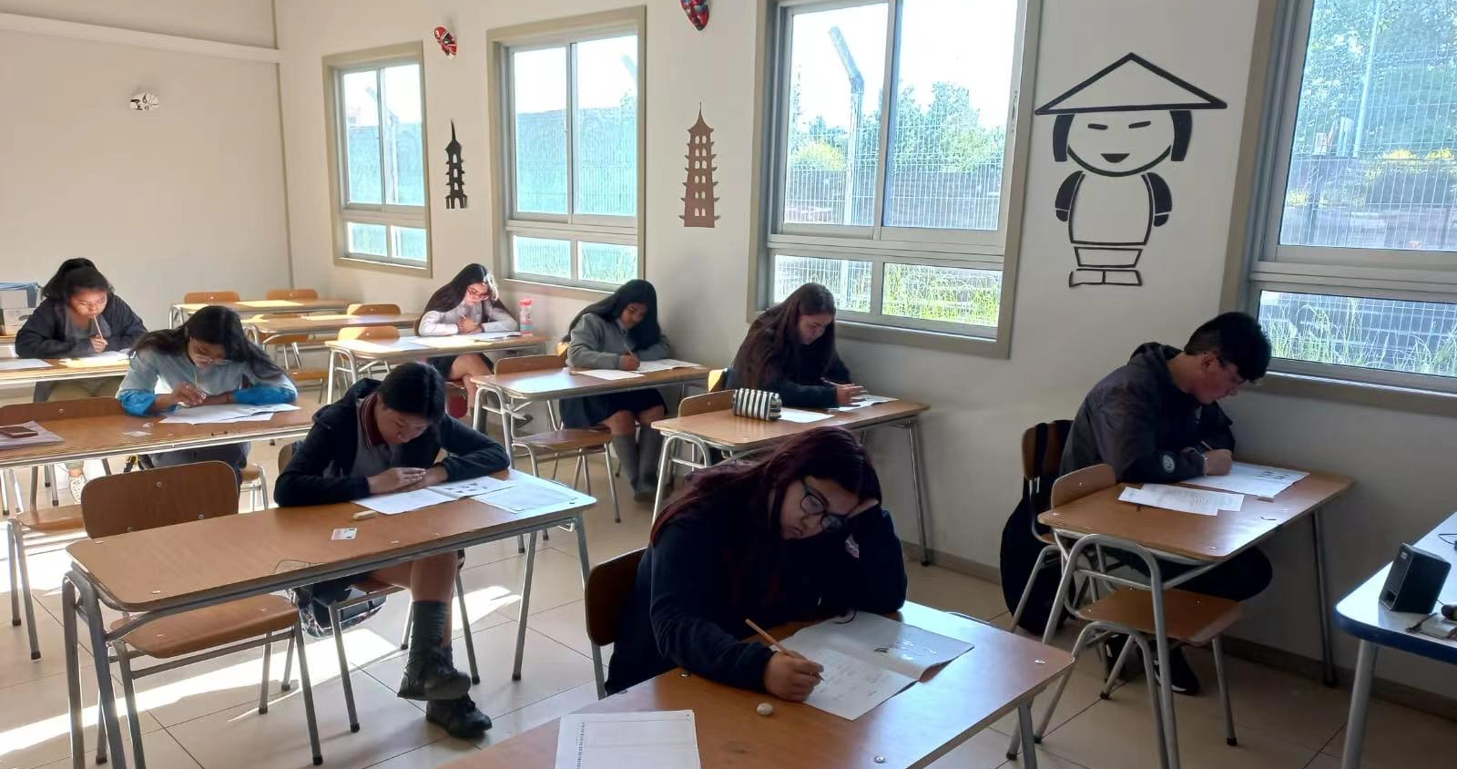 Alumnos adolescentes en una sala de clases de la escuela rindiendo el examen de chino HSK.